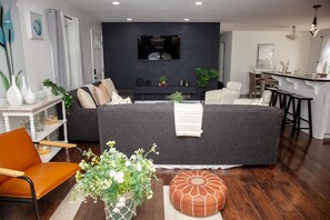 A modern living room with a dark grey sofa, a white armchair, and a wooden dining table. - Comfortable Marietta Family Home (Marietta)