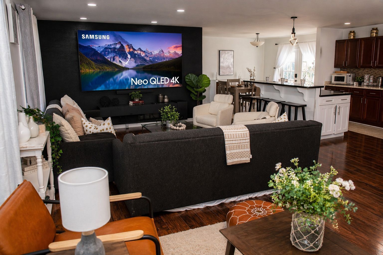 A modern living room with a black sofa, a coffee table, and a TV mounted on the wall.