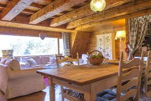 A cozy wooden interior with a dining table, chairs, and a sofa. - Pescasseroli Appartamento Panoramico (Pescasseroli)