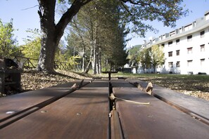 A park with a metal bench, trees, and a building in the background. - Pescasseroli Appartamento Panoramico (Pescasseroli)