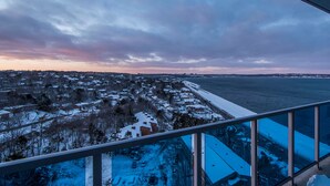 A snowy landscape with a view of a body of water and a distant shoreline. - Icon Bay (Halifax)