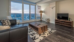 A modern living room with a large window, a flat-screen TV, a wooden coffee table, and a sofa. - Icon Bay (Halifax)
