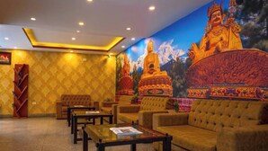 Una hall d'albergo con un grande murale raffigurante Buddha, zone relax e una reception.