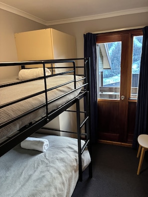 Ett rum med en våningssäng, en dörr och ett litet bord.