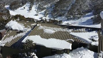 A mountain landscape with snow-covered slopes and a building with a sloped roof.