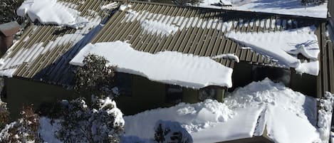 Un paysage de montagne avec des pentes enneigées et un bâtiment doté d’un toit en pente.