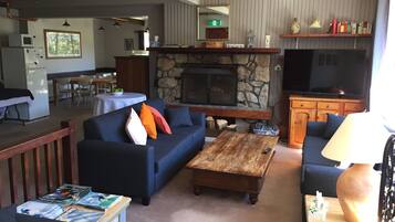 A living room with a stone fireplace, sofas, a coffee table, and a television.