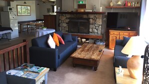 A living room with a stone fireplace, sofas, a coffee table, and a television.
