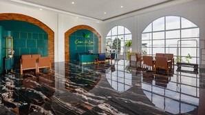 Um saguão de hotel com piso de mármore, áreas de estar e grandes janelas.
