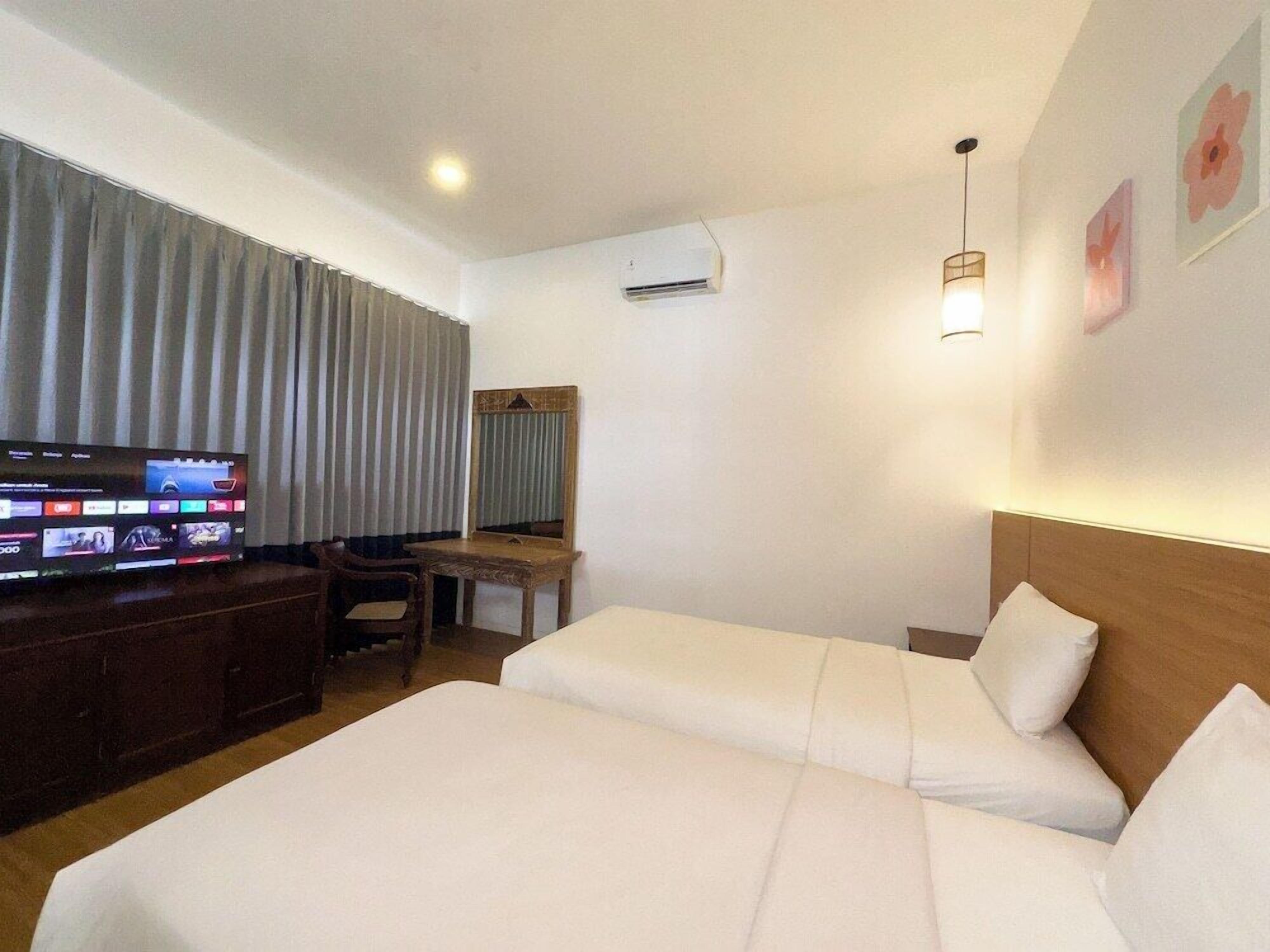 A hotel room with two beds, a TV, a desk, and a chair.