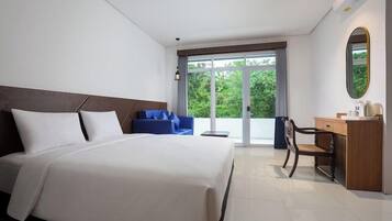A hotel room with a bed, a blue chair, a desk, and a view through a glass door.