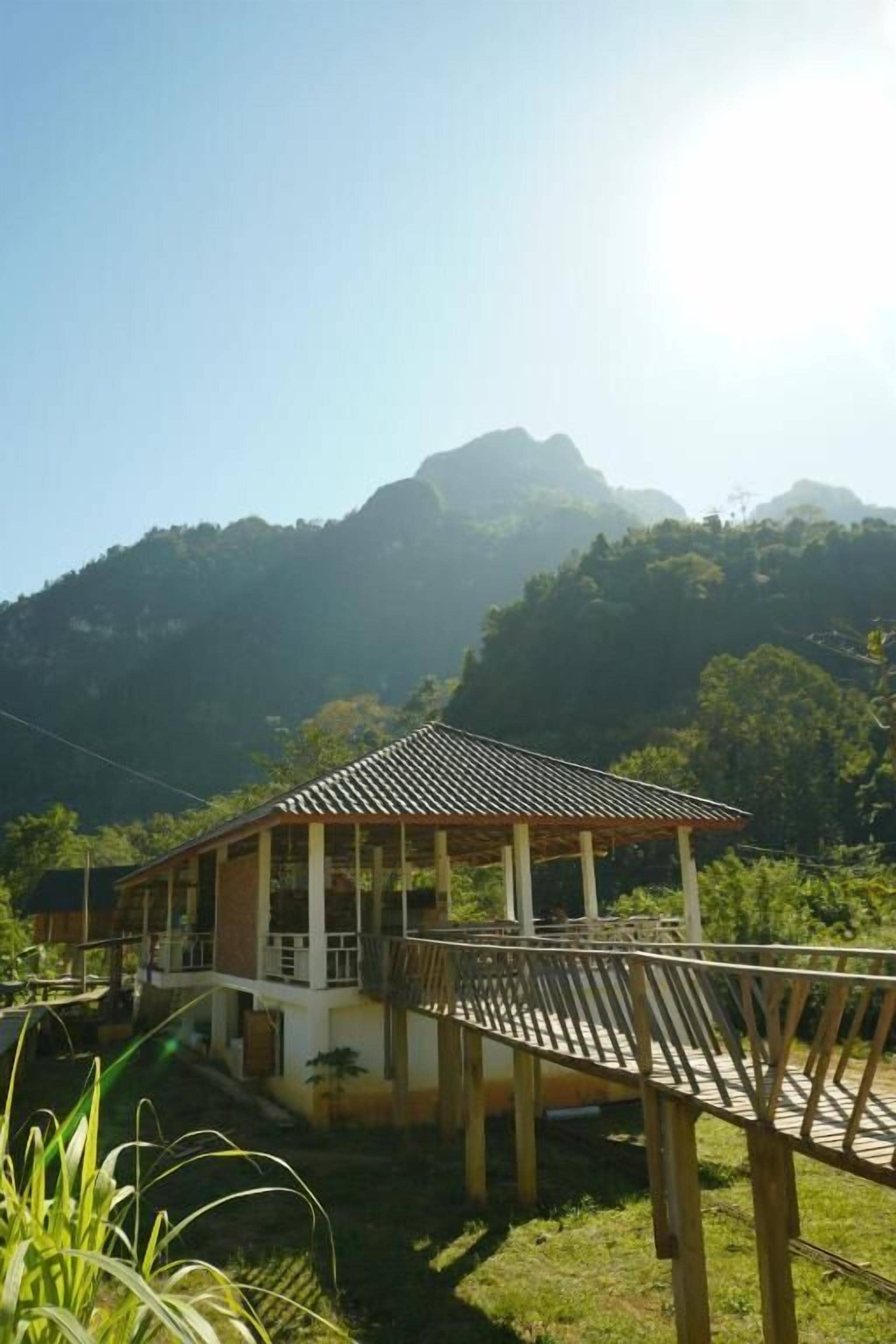 Uma casa com deck de madeira, cercada por vegetação e montanhas.