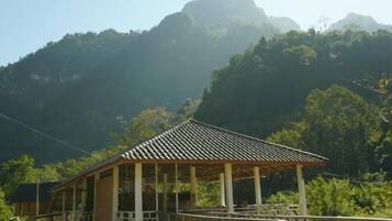 Uma casa com deck de madeira, cercada por vegetação e montanhas.