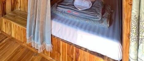 Eine Holzhütte mit Etagenbett, einem fenster mit Vorhängen und Holzboden.