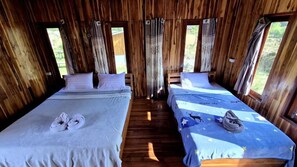 Una stanza di un cottage in legno con due letti, ognuno con cuscini e asciugamani.