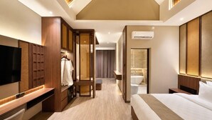 A hotel room with a bed, a TV, a wardrobe, and a bathroom with a bathtub. - Sapphire Boutique Hotel Kudus (Kudus)