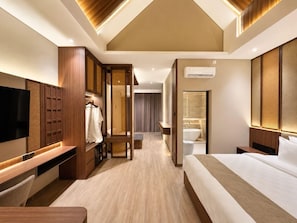Ein modernes Hotelzimmer mit einem großen Bett, einem Fernseher, einem Kleiderschrank und einem Badezimmer.