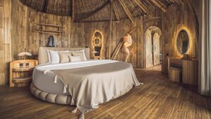 A room with a large bed, wooden walls, a curved ceiling, and a small vanity with a mirror. - Equipoise Resort Ubud by Ini Vie Hospitality (Tegallalang)