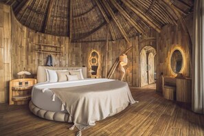 A room with a large bed, wooden walls, a curved ceiling, and a small vanity with a mirror. - Equipoise Resort Ubud by Ini Vie Hospitality (Tegallalang)