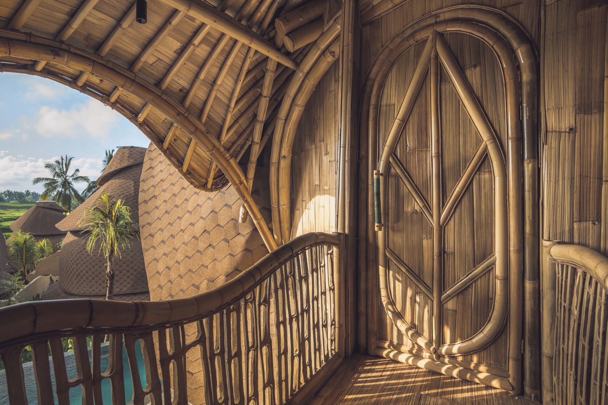 A wooden staircase with a geometric design, leading to a large arched doorway.