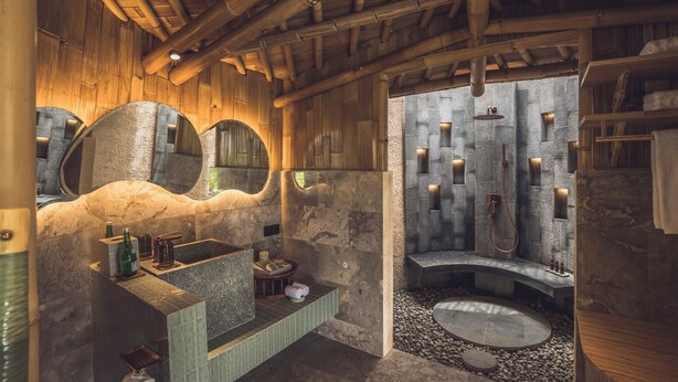 Un baño rústico con un lavabo de piedra, un espejo grande y un box de ducha de piedra.