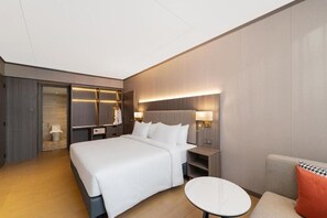 A modern hotel room with a large bed, bedside tables, a round table, and a sofa. - Harris Hotel and Suites Nagoya Batam (Batam)