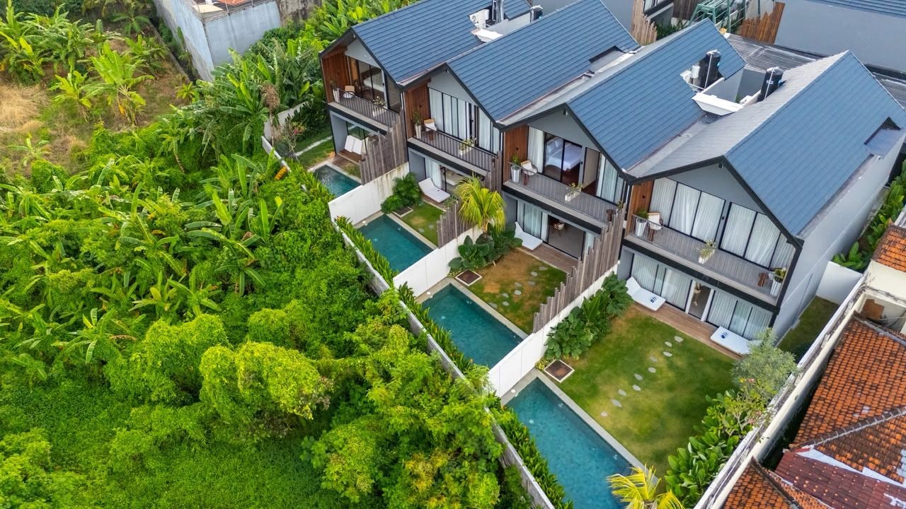 Um edifício residencial moderno com piscina, rodeado por vegetação exuberante.