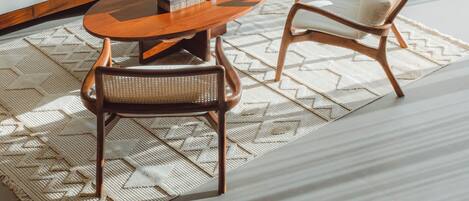 Una sala moderna con un sofá seccional, una mesa de centro de madera y dos sillones de mimbre.