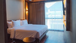 Una habitación de hotel con una cama, una mesita de noche, una ventana con cortinas y vistas al exterior.