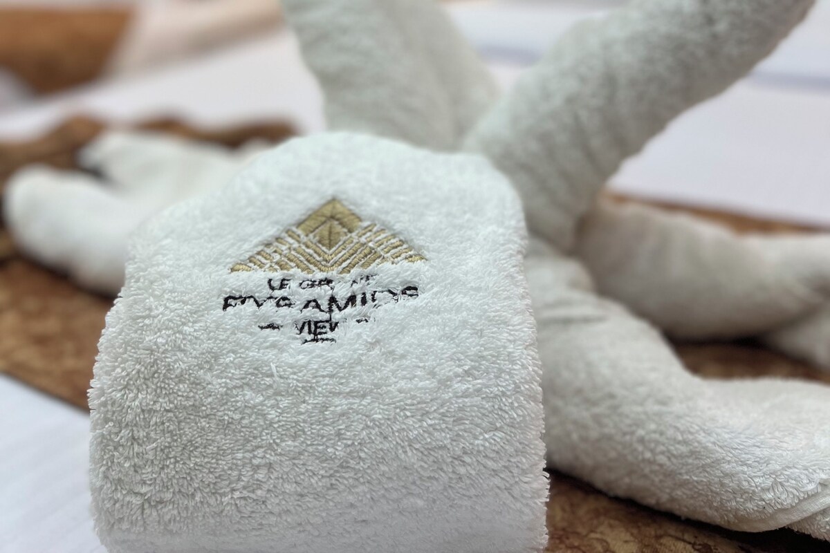 A swan-shaped towel with a logo and text, placed on a wooden surface.