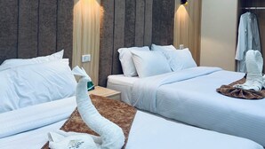 Een hotelkamer met twee bedden, een houten accentmuur, wandlampen, een badjas en een handdoek op de vloer.