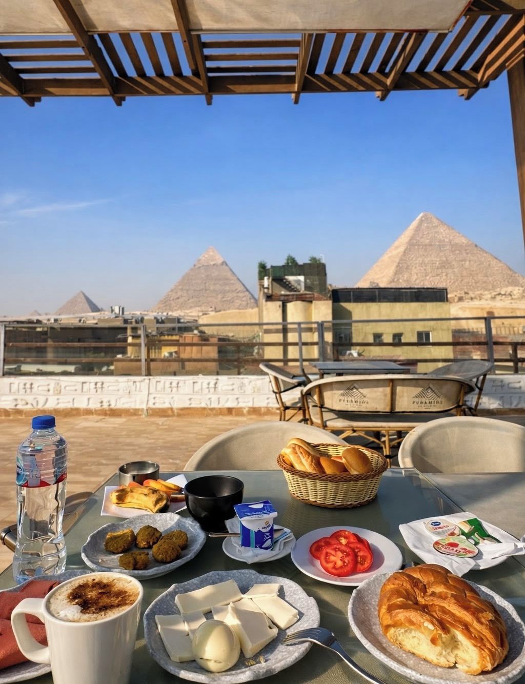 Une table dressée avec de la nourriture et des boissons, offrant une vue sur les pyramides.