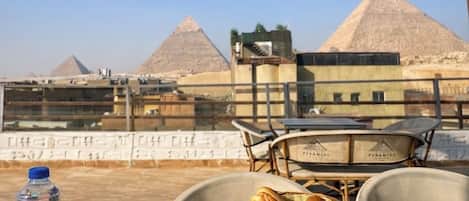 Une table dressée avec de la nourriture et des boissons, offrant une vue sur les pyramides.