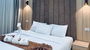 A modern hotel room with a bed, a nightstand, an air conditioning unit, and wall-mounted lighting.