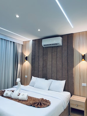 A modern hotel room with a bed, a nightstand, an air conditioning unit, and wall-mounted lighting. - Le Grand Pyramids View & Suites (Giza)