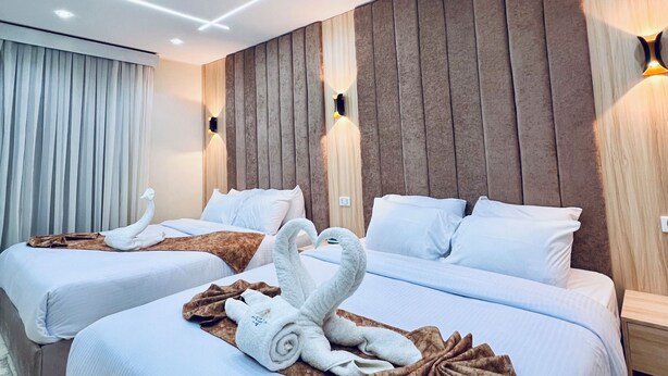 A hotel room with two beds, each with white linens and a swan-shaped towel arrangement.