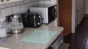 A kitchen with a washing machine, a coffee maker, and a toaster. - Spacious 4BR Stay in Morden Contractors and Group (Morden)