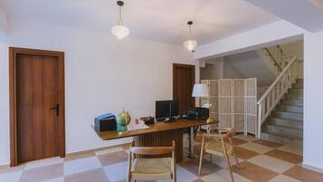 A room with a wooden desk, two chairs, a globe, and a computer. There is a staircase in the background.