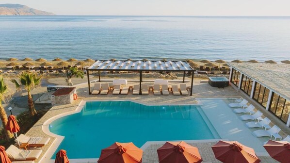 A pool area with lounge chairs and umbrellas, overlooking a body of water.