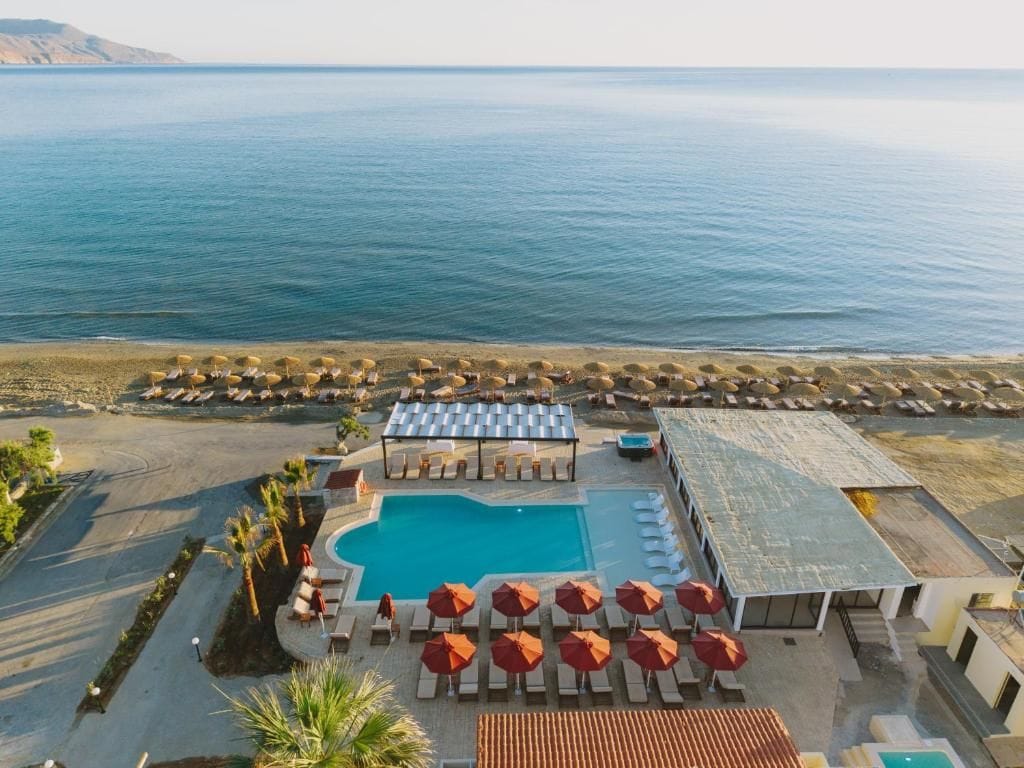 Un resort con piscina, tumbonas, sombrillas y vistas al mar.
