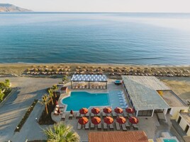 Un resort con piscina, tumbonas, sombrillas y vistas al mar.