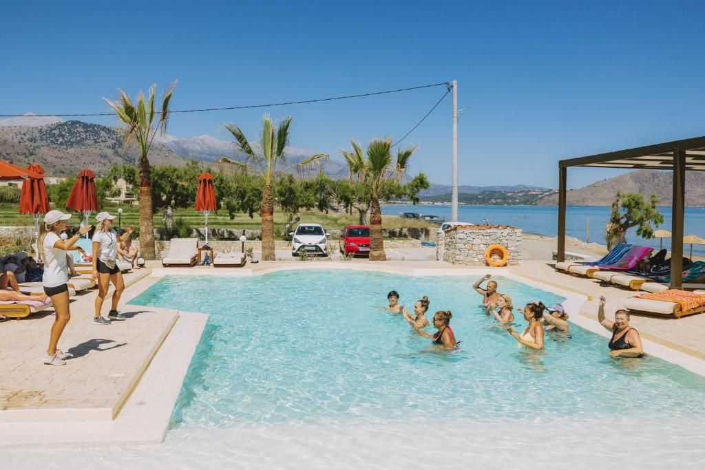 A swimming pool with people around it, a clear sky, and a mountainous landscape in the background.