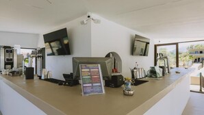 Un espace d’accueil moderne avec un téléviseur à écran plat, un kiosque numérique et une machine à café.