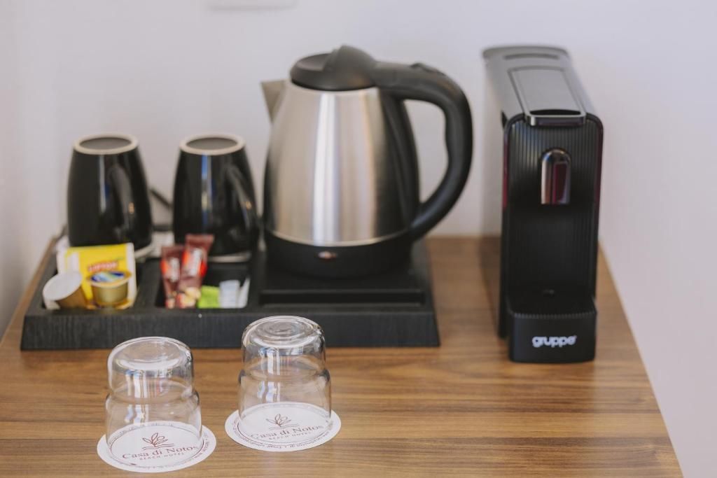 A coffee station with a coffee maker, two cups, a kettle, and a toaster.