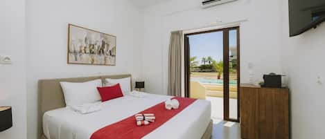 A hotel room with a bed, a painting, a desk, and a view of a pool.
