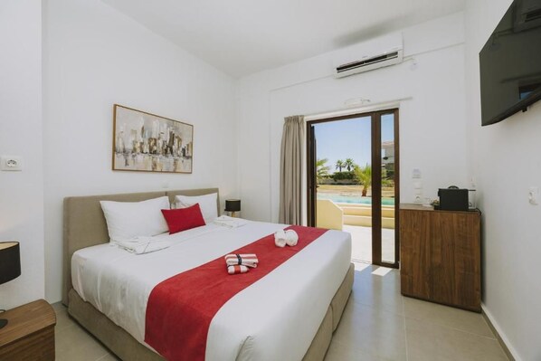 A hotel room with a bed, a painting, a desk, and a view of a pool.