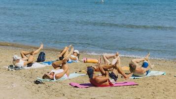 People sunbathing on beach towels near the water.