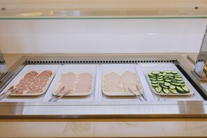 A buffet with various food items including sliced meats and vegetables.