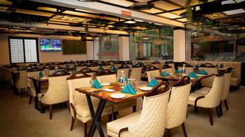 A restaurant with multiple tables and chairs, a television screen, and a sign indicating a smoking area.