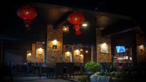 An outdoor seating area with brick walls, hanging red lanterns, and a television screen. - 21 Karimun (Karimun)